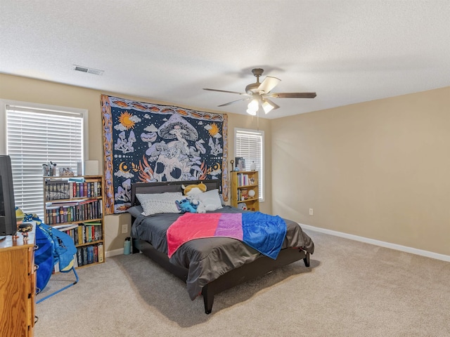 carpeted bedroom with ceiling fan and a textured ceiling