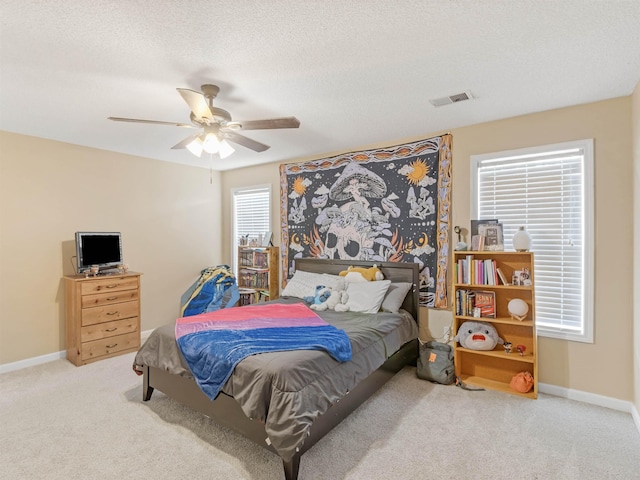 carpeted bedroom with ceiling fan and a textured ceiling