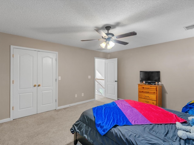 bedroom featuring a textured ceiling, a closet, ceiling fan, and light colored carpet