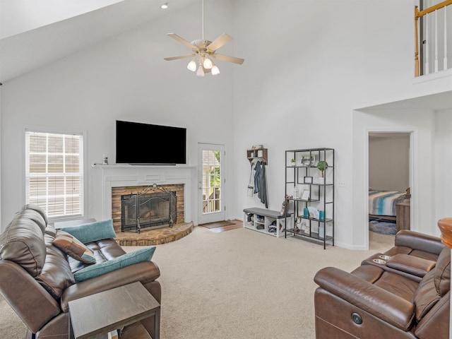 carpeted living room with ceiling fan, a fireplace, and high vaulted ceiling