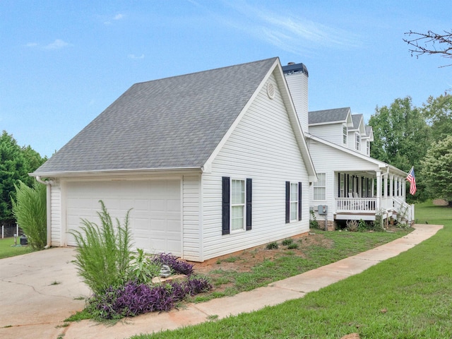 view of side of property with a lawn, a garage, and covered porch