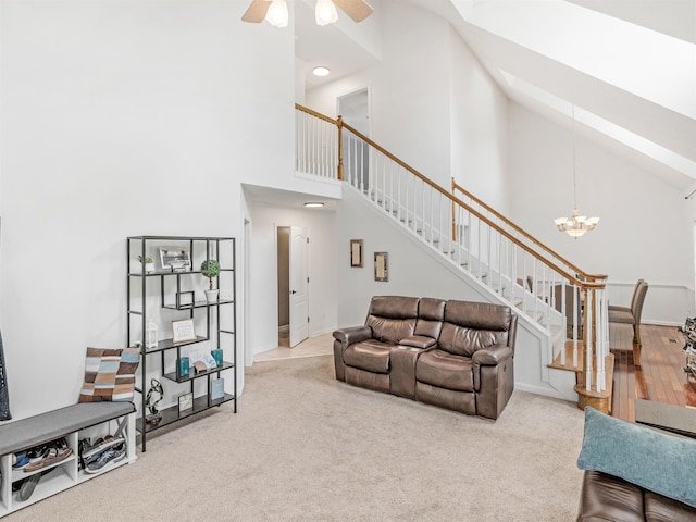 living room featuring carpet flooring, ceiling fan with notable chandelier, and high vaulted ceiling