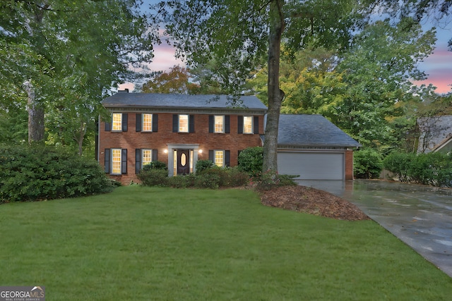 colonial house featuring a lawn and a garage