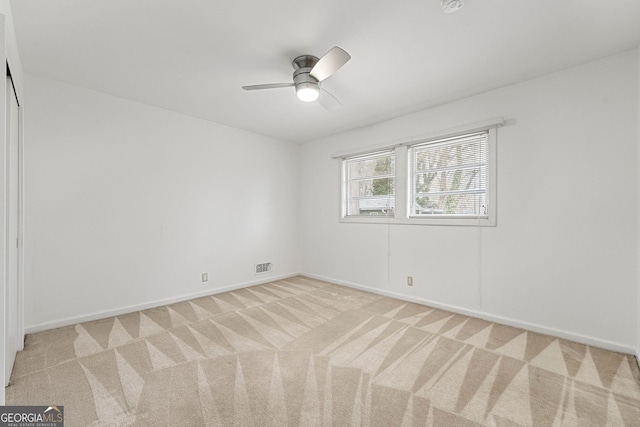 spare room featuring light carpet and ceiling fan