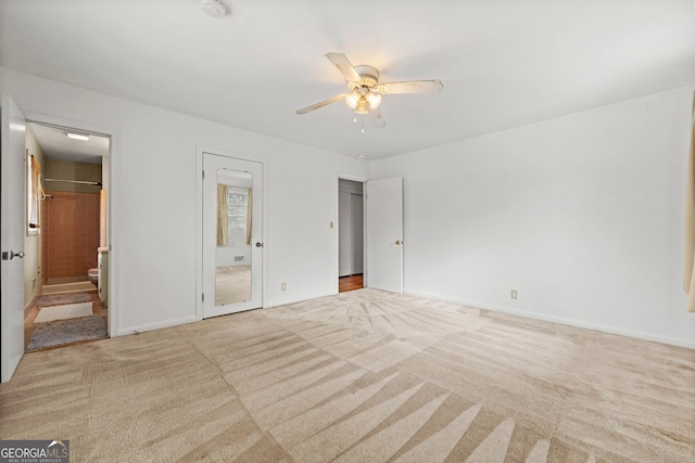 unfurnished bedroom with ceiling fan, light colored carpet, and ensuite bath