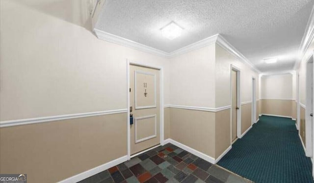 hall with a textured ceiling and ornamental molding