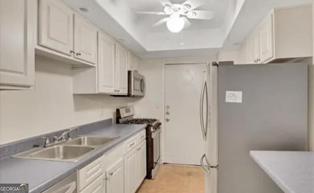 kitchen with a tray ceiling, white cabinetry, ceiling fan, and appliances with stainless steel finishes