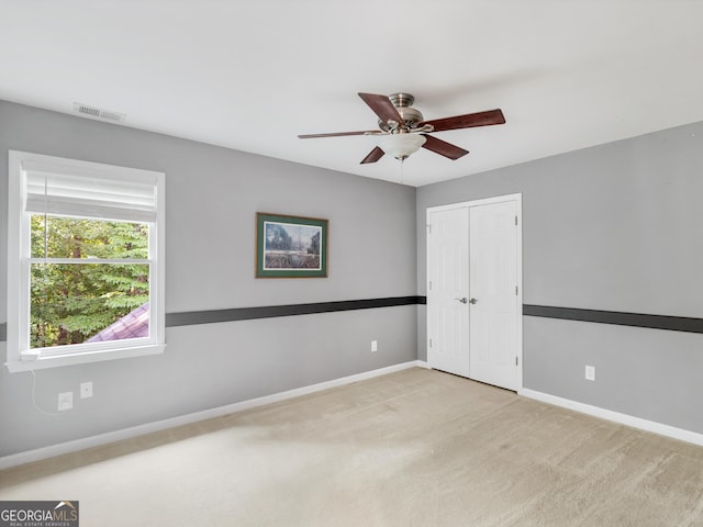 empty room featuring ceiling fan and light colored carpet