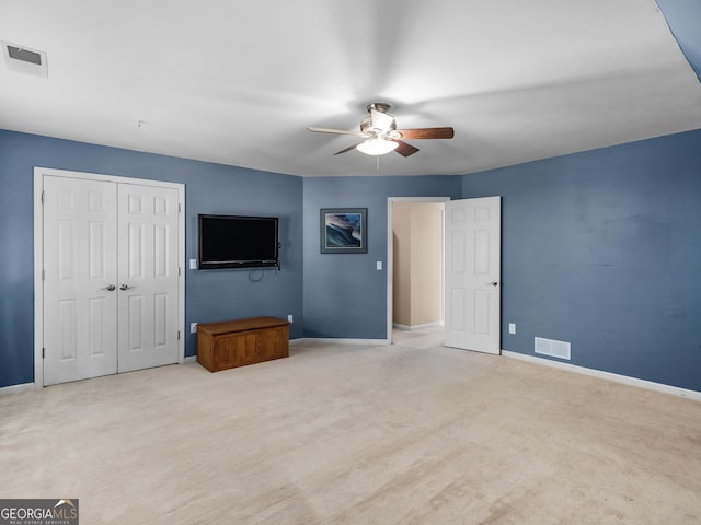 unfurnished bedroom with ceiling fan, light carpet, and a closet