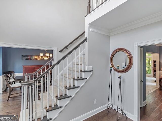 stairs with hardwood / wood-style floors, crown molding, and a chandelier