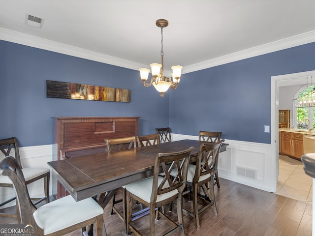 dining space featuring hardwood / wood-style floors, sink, crown molding, and a chandelier