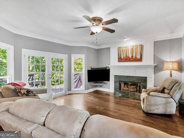 living room featuring ceiling fan, hardwood / wood-style floors, a high end fireplace, and ornamental molding