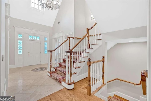 entryway featuring tile patterned flooring, high vaulted ceiling, and a notable chandelier