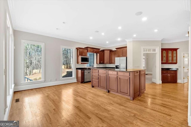 kitchen featuring crown molding, a center island, stainless steel appliances, and light hardwood / wood-style flooring