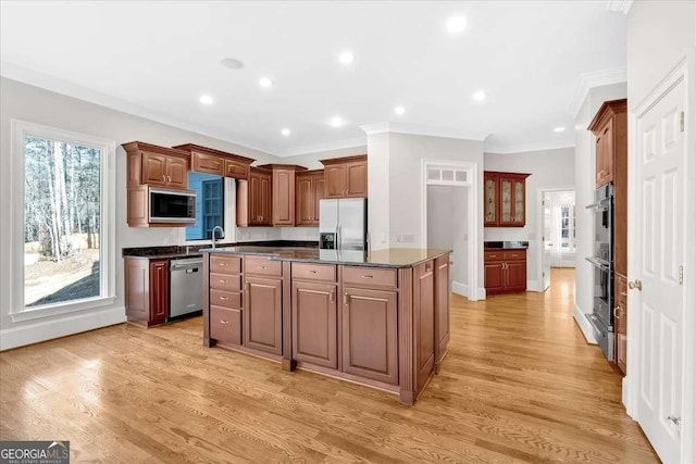 kitchen with a center island, stainless steel appliances, dark stone counters, and light hardwood / wood-style flooring