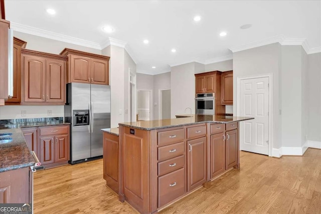 kitchen featuring appliances with stainless steel finishes, a kitchen island, ornamental molding, and dark stone counters