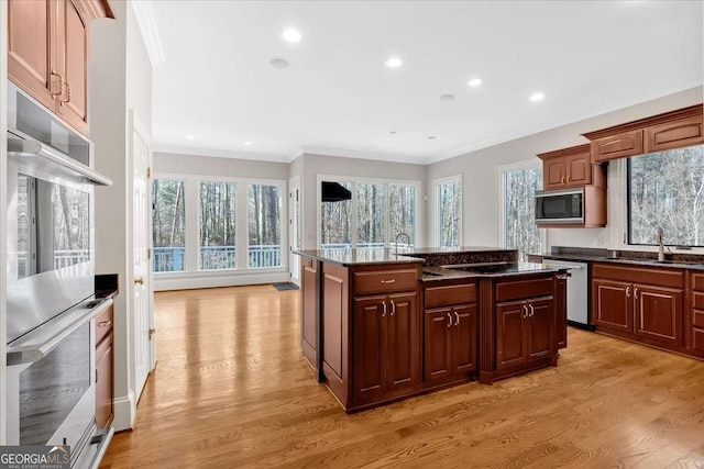 kitchen featuring sink, crown molding, a kitchen island with sink, appliances with stainless steel finishes, and light wood-type flooring