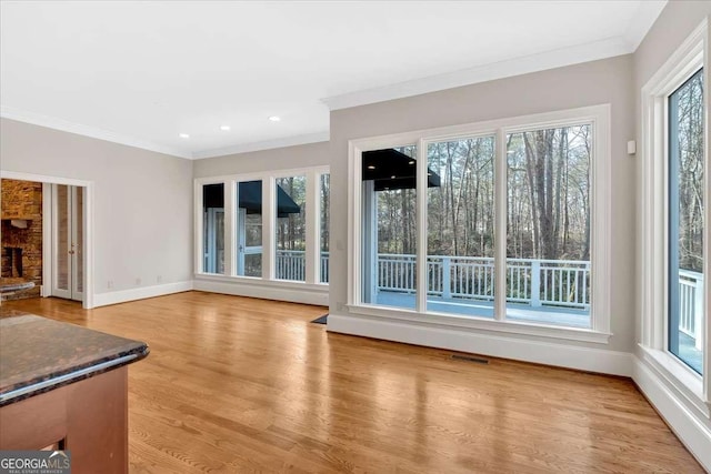 unfurnished living room with a fireplace, light hardwood / wood-style floors, and ornamental molding