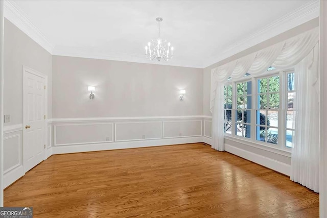 unfurnished dining area featuring wood-type flooring, ornamental molding, and an inviting chandelier