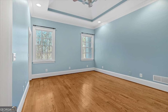 unfurnished room featuring light hardwood / wood-style flooring, a raised ceiling, and ornamental molding