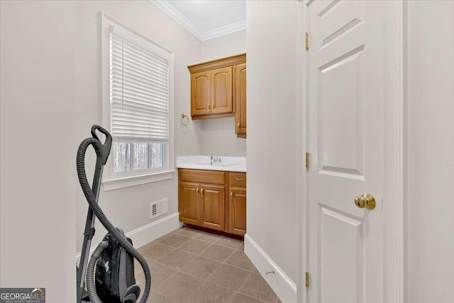 washroom with ornamental molding, sink, and light tile patterned floors