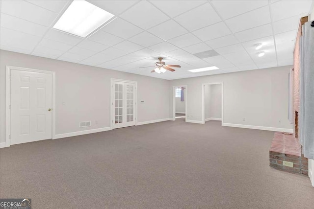 basement featuring ceiling fan, a drop ceiling, and carpet