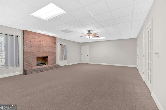 unfurnished living room with a paneled ceiling, ceiling fan, a fireplace, and carpet