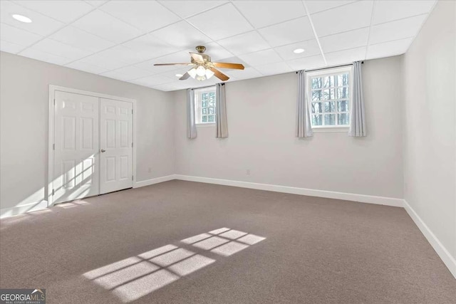 carpeted empty room with a drop ceiling and ceiling fan