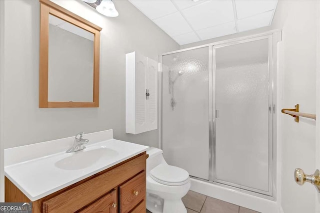 bathroom featuring tile patterned floors, an enclosed shower, a drop ceiling, vanity, and toilet