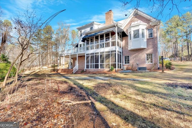 rear view of house featuring a yard, a balcony, and a sunroom