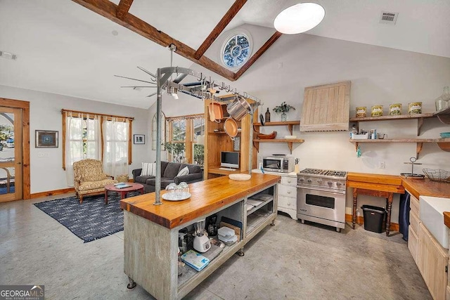 kitchen featuring beam ceiling, butcher block counters, ceiling fan, stainless steel appliances, and a kitchen island