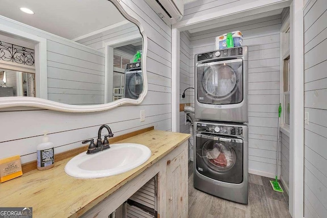 laundry room with wood walls, sink, stacked washing maching and dryer, and wood-type flooring