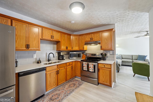 kitchen with ceiling fan, sink, a textured ceiling, and appliances with stainless steel finishes