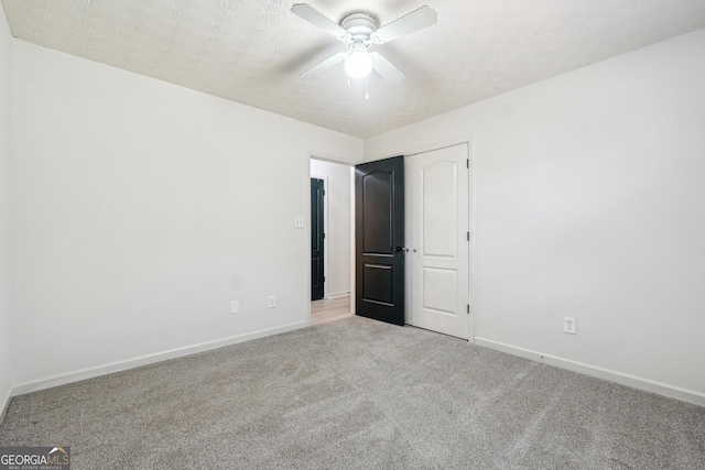 unfurnished bedroom featuring ceiling fan, light carpet, and a textured ceiling