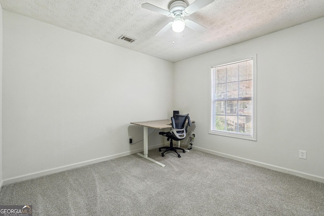 unfurnished office featuring carpet flooring, a textured ceiling, and ceiling fan