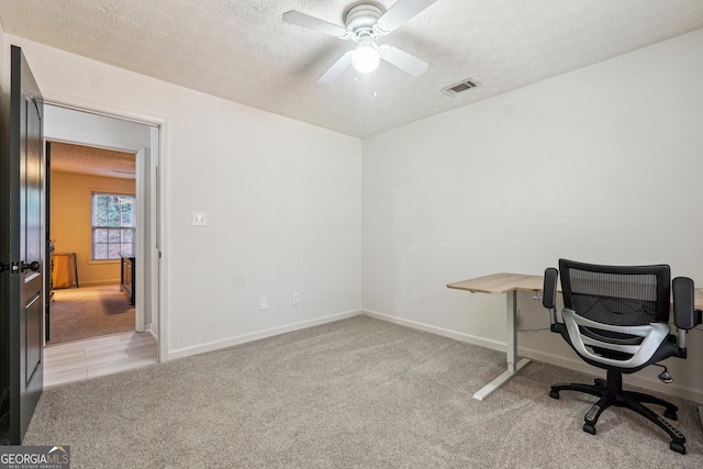 office featuring light carpet, a textured ceiling, and ceiling fan