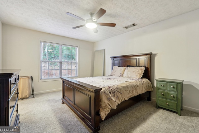 carpeted bedroom with ceiling fan and a textured ceiling