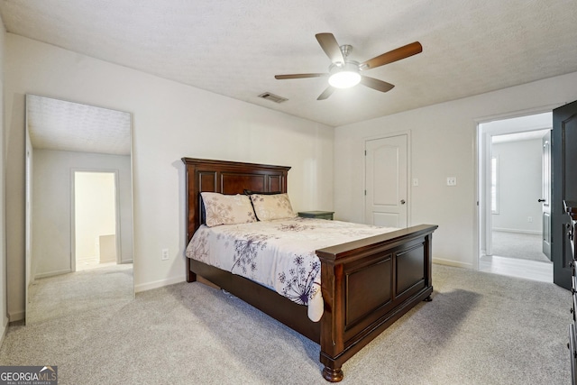 bedroom featuring ceiling fan, light carpet, and a textured ceiling