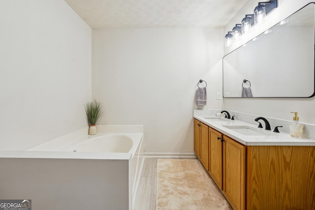 bathroom with vanity, a textured ceiling, and a washtub