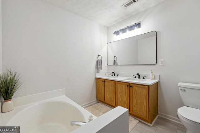 bathroom with vanity, a textured ceiling, toilet, and a washtub