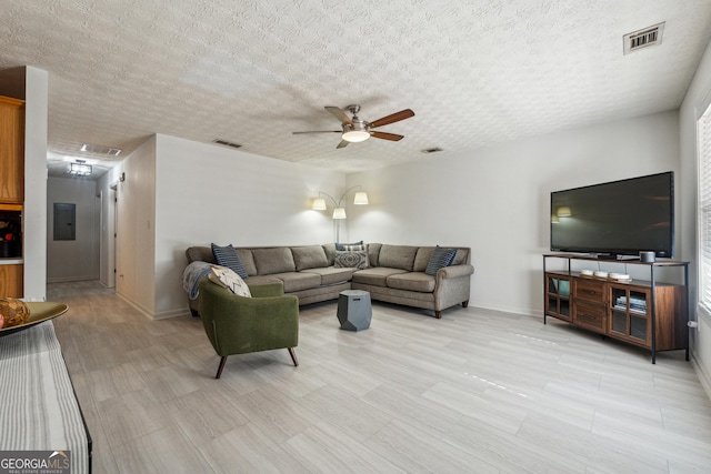 living room with a textured ceiling, electric panel, and ceiling fan