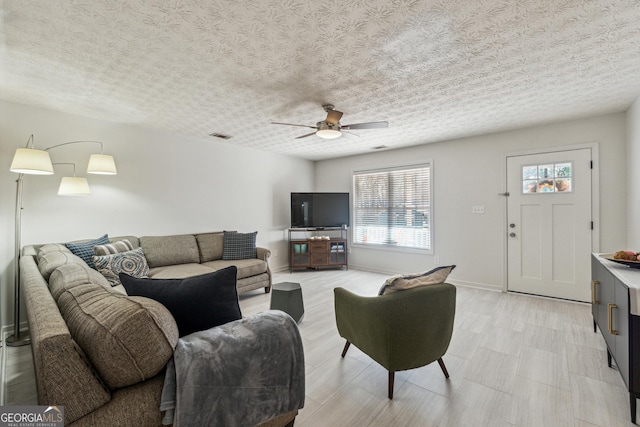 living room with ceiling fan and a textured ceiling