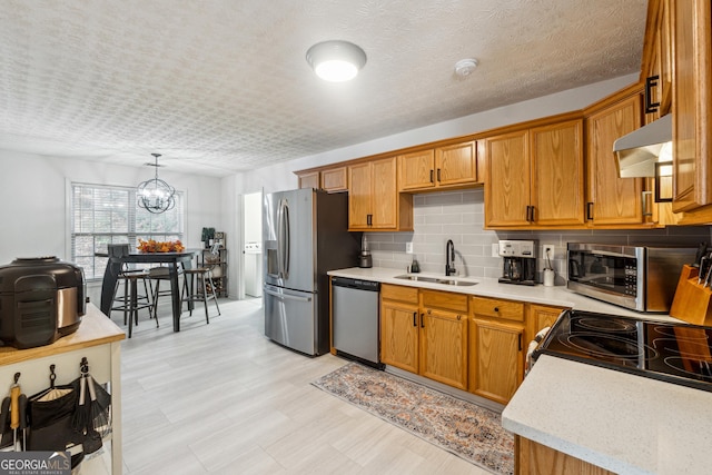 kitchen featuring sink, stainless steel appliances, a chandelier, decorative light fixtures, and exhaust hood