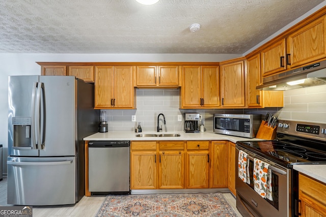 kitchen featuring decorative backsplash, appliances with stainless steel finishes, a textured ceiling, and sink