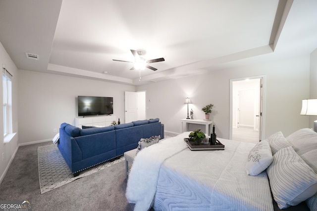 carpeted bedroom featuring a raised ceiling and ceiling fan