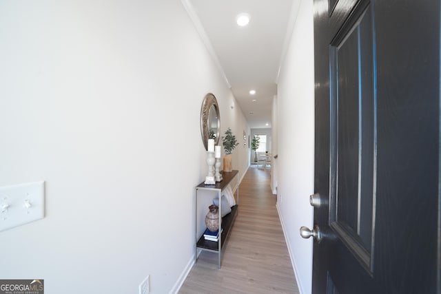 hall with light hardwood / wood-style floors and ornamental molding