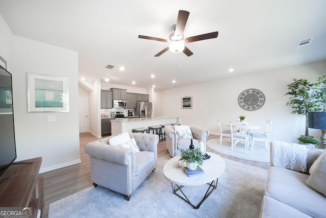 living room featuring ceiling fan and light hardwood / wood-style floors