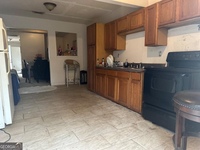 kitchen with electric range, white refrigerator, and sink