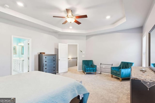 carpeted bedroom featuring ceiling fan, a raised ceiling, and ensuite bathroom