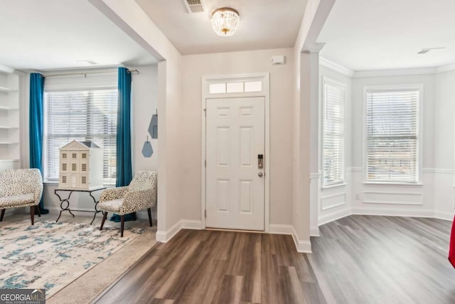 foyer entrance with dark hardwood / wood-style flooring, ornamental molding, and a chandelier